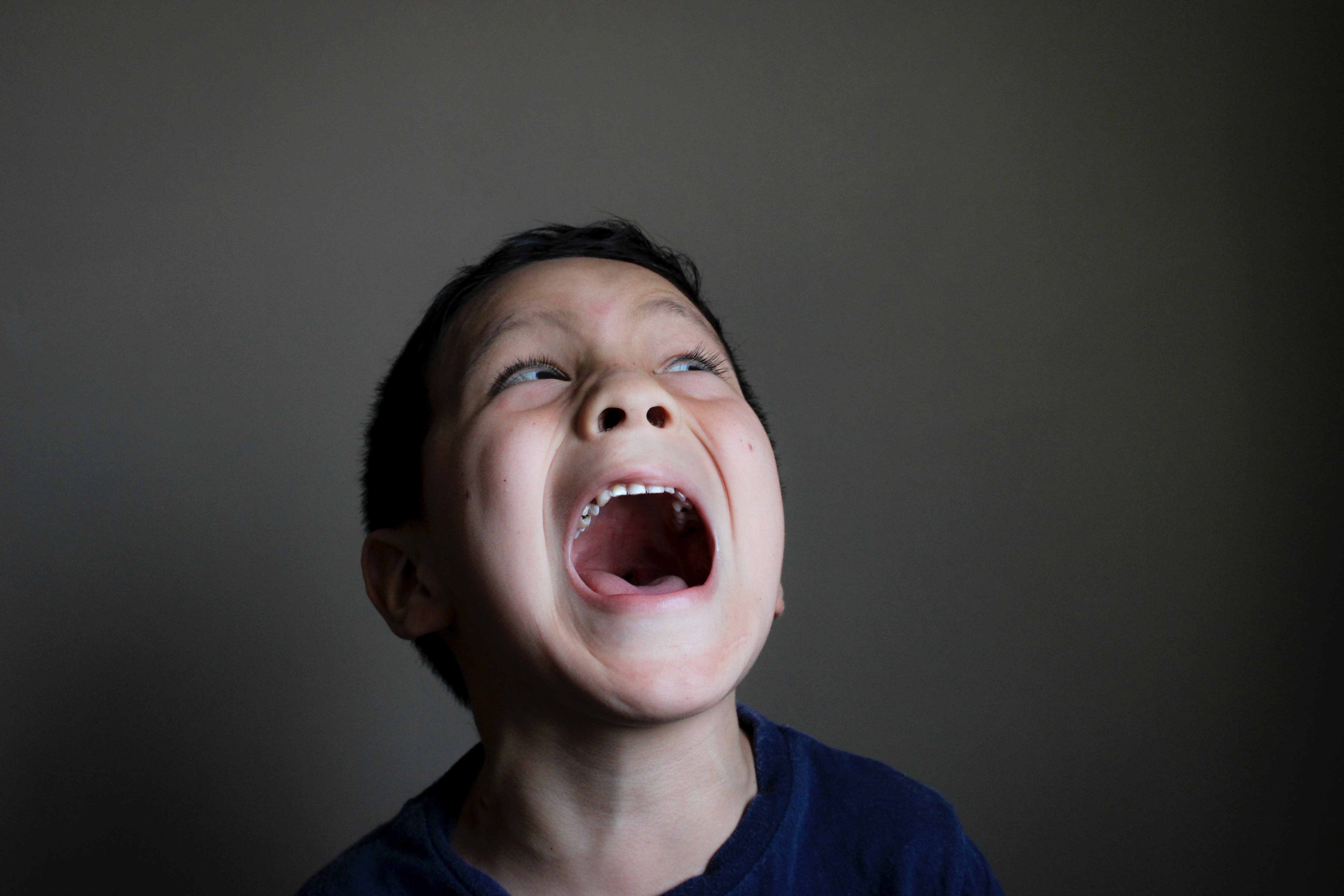 Junge schreit laut mit geöffnetem Mund, Ausdruck von starken Emotionen wie Wut, Frustration oder Überforderung bei Kindern