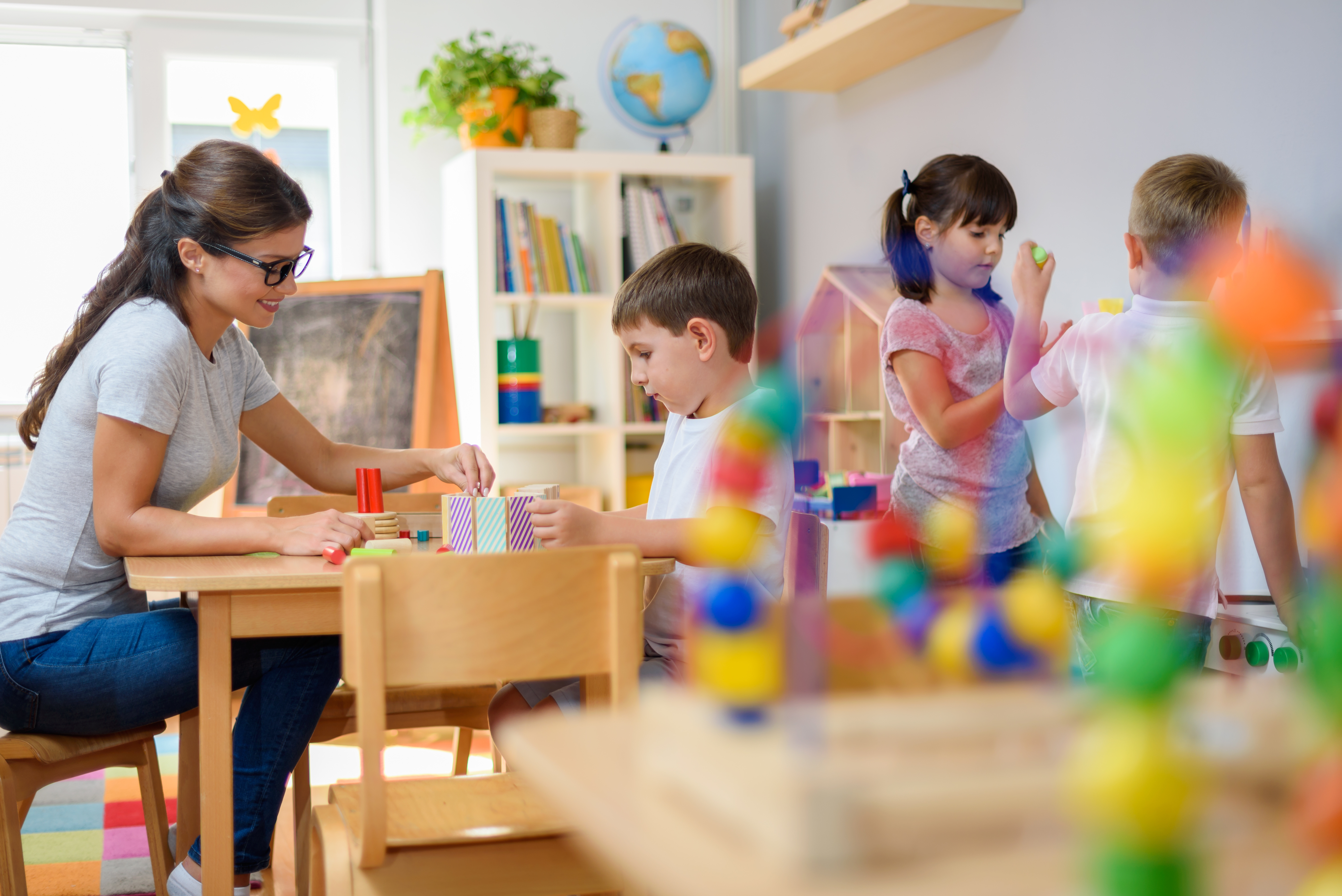 Erzieherin betreut Kinder beim Spielen und Lernen im Kindergarten, pädagogische Förderung mit Bausteinen und kreativen Aktivitäten im Gruppenraum