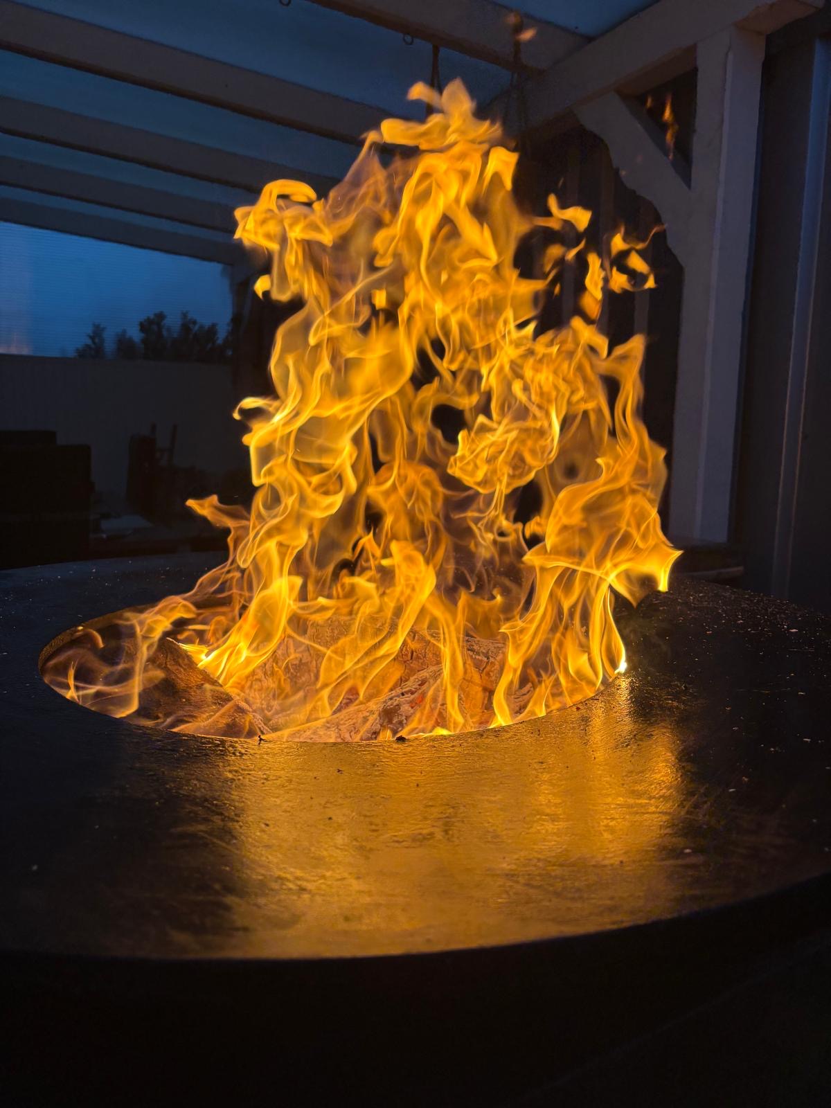 Lodernde Flammen auf Grillplatte bei Nacht, intensives Feuer für BBQ und Outdoor Kochen mit hoher Hitze