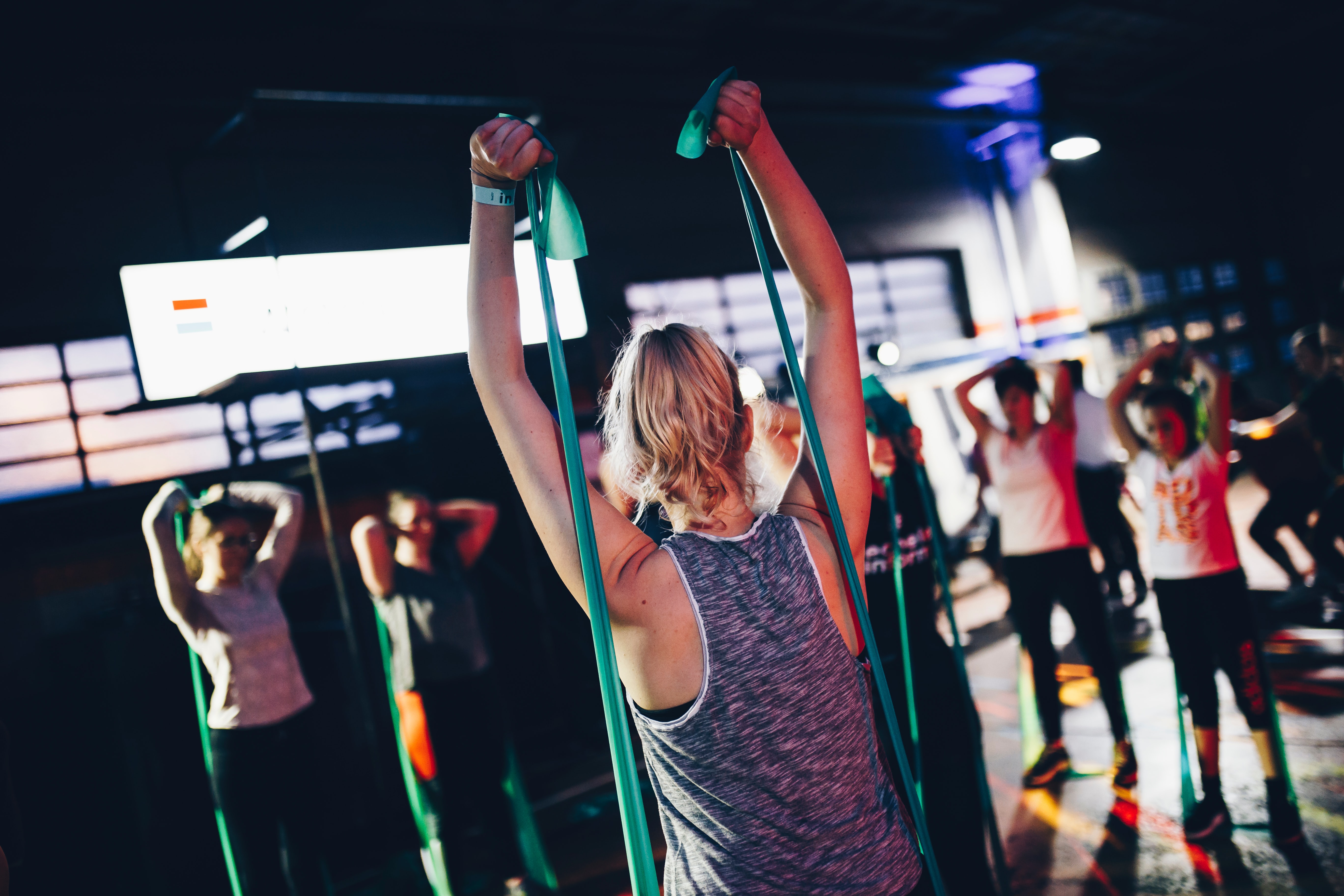 Gruppe trainiert gemeinsam mit Fitnessbändern im Kursraum, dynamisches Ganzkörpertraining für Kraft, Ausdauer und Motivation in der Gruppe