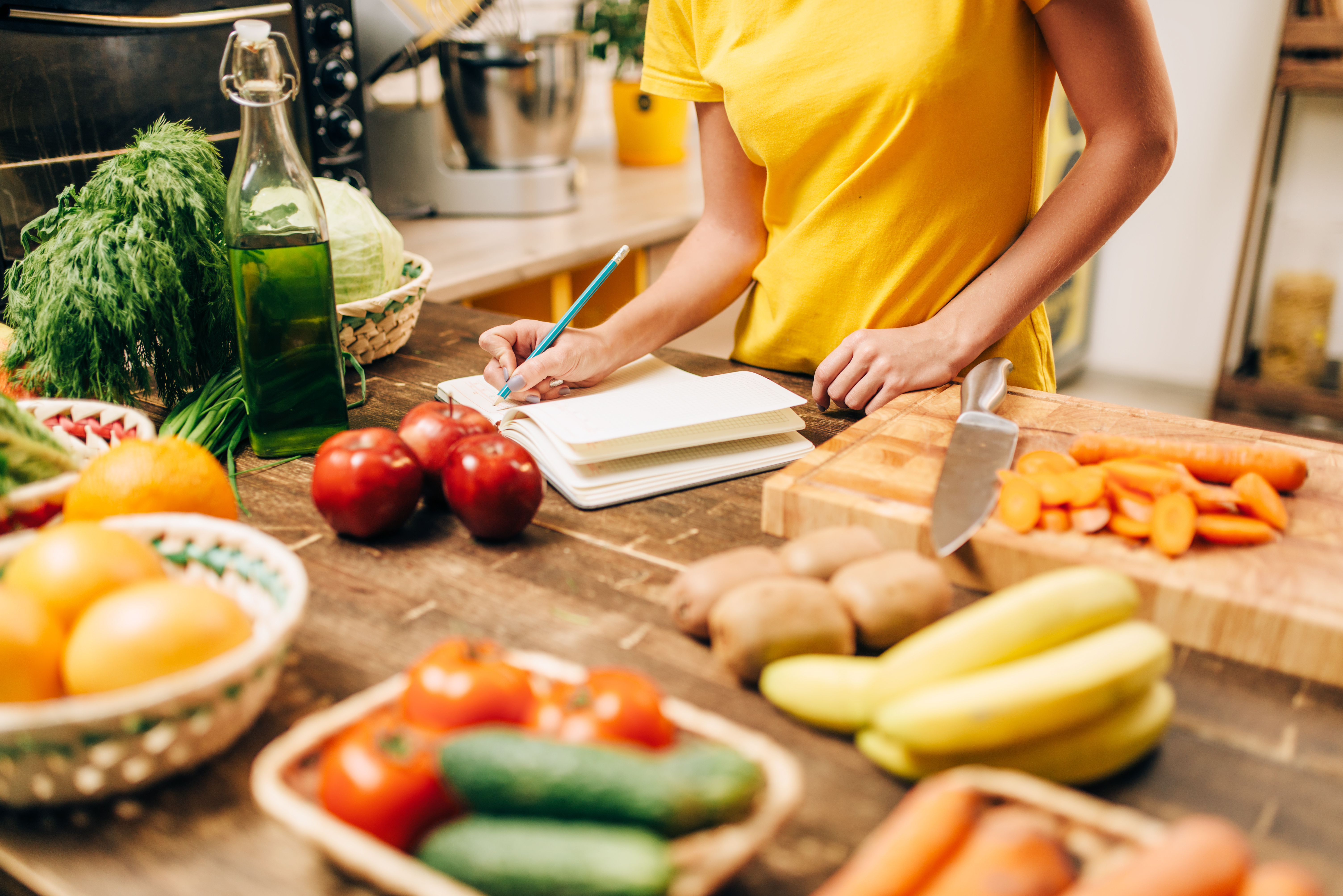 Person plant gesunde Mahlzeiten mit frischem Obst und Gemüse in der Küche, bewusste Ernährung und Vorbereitung ausgewogener Speisen im Alltag