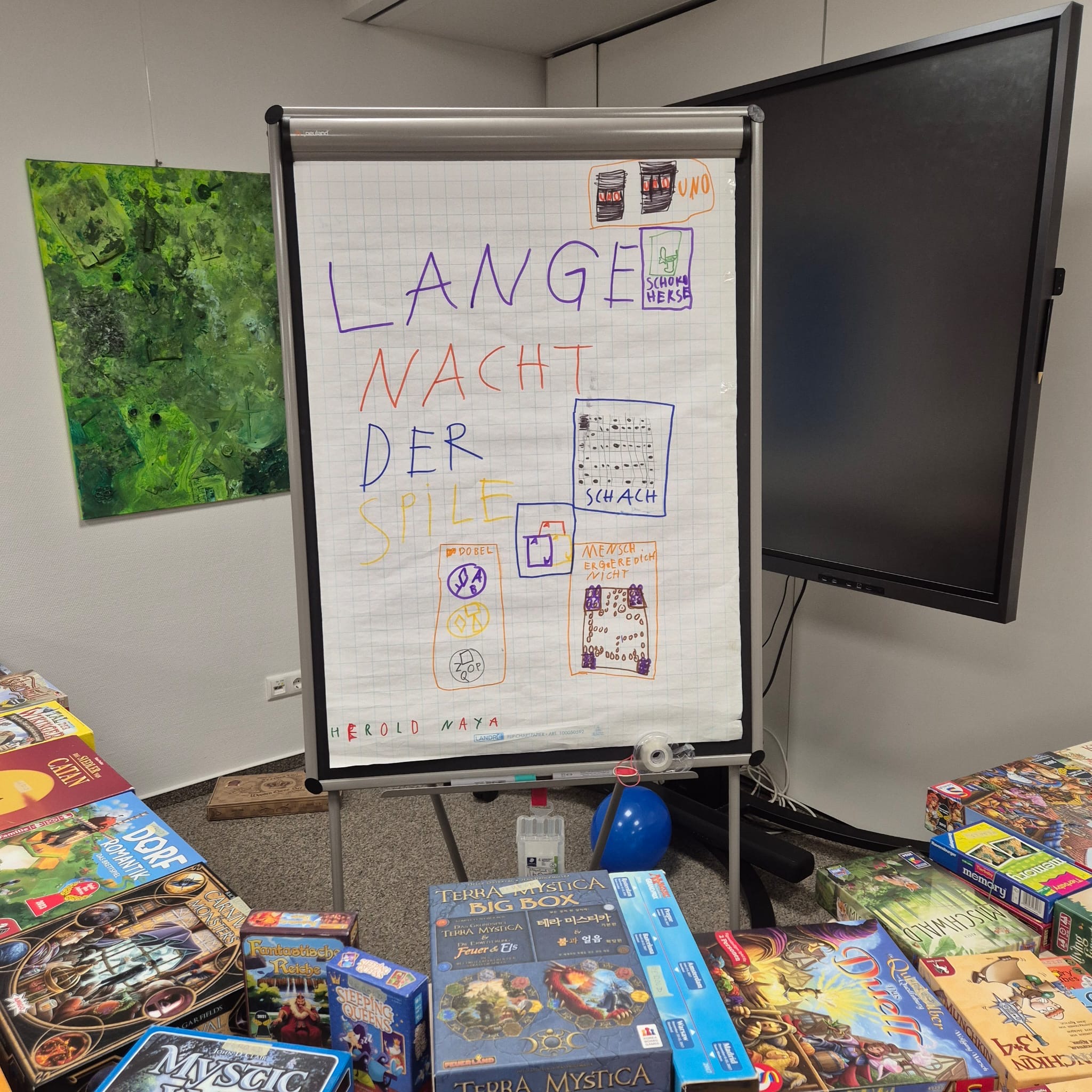 Flipchart mit Schriftzug "Lange Nacht der Siele", auf dem Tisch liegen verschiedene Spiele für gemeinsames Lernen, Austausch und kreative Gruppenarbeit