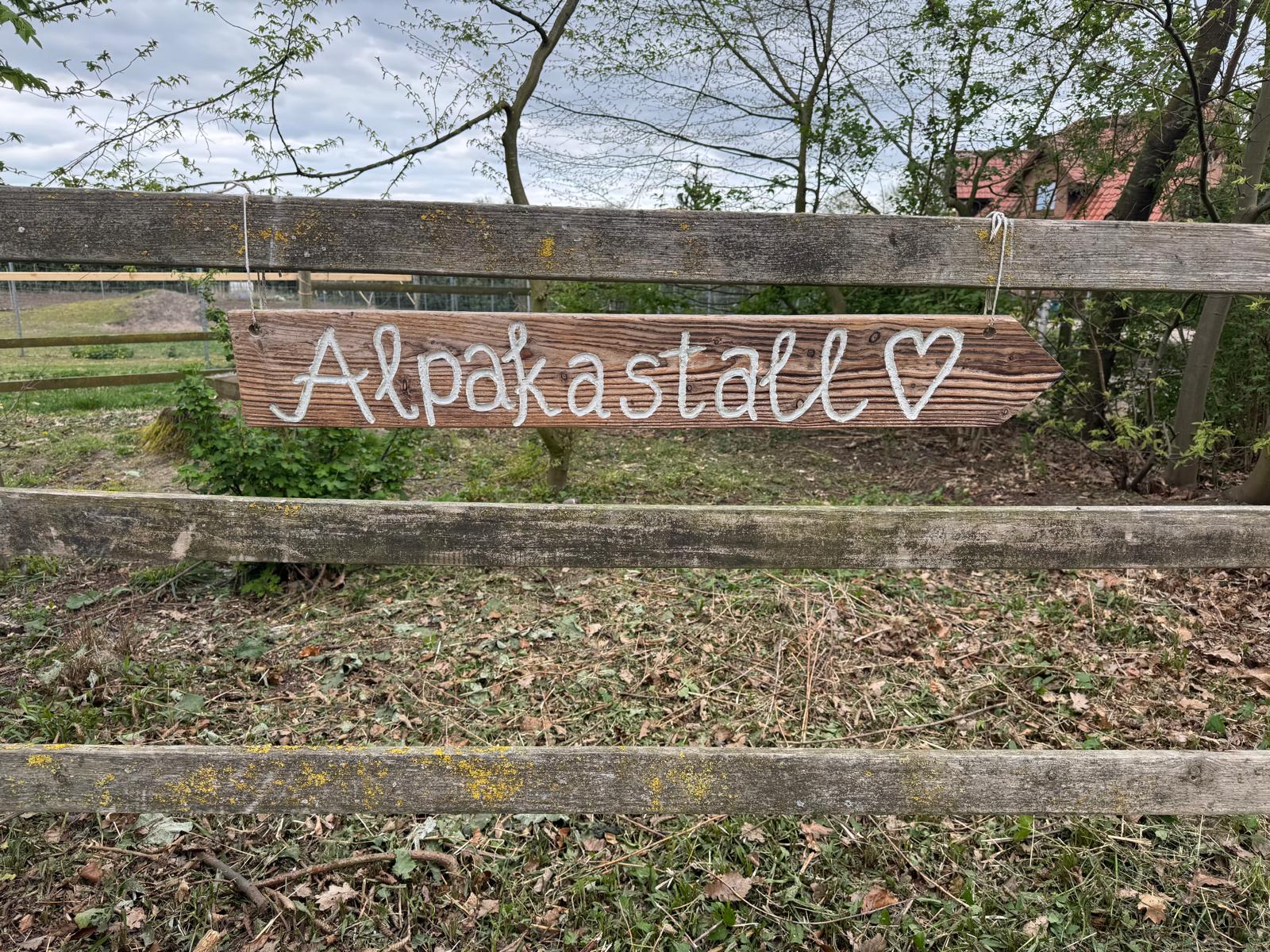 Ein Schild auf dem das Wort Alpakastall steht.
